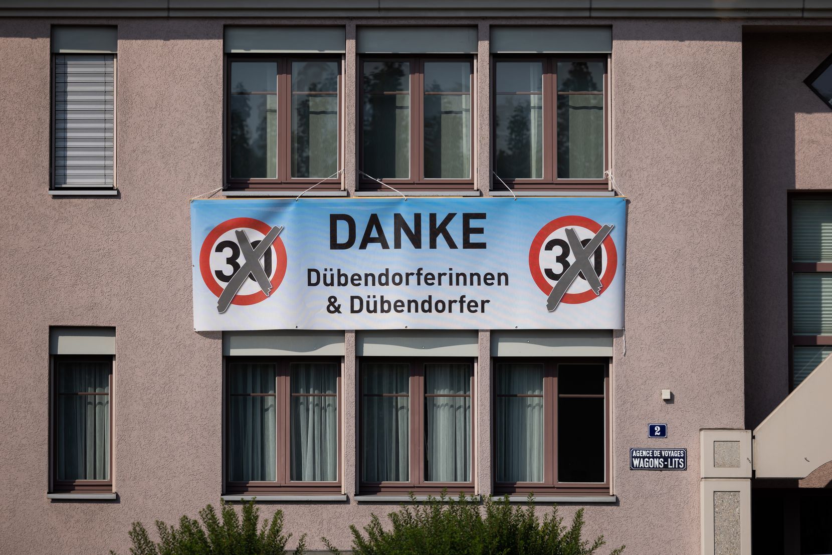 Ein Plakat an einer Hausfassade.